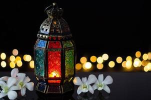 lykta med vit orkide blomma på bokeh ljus bakgrund för de muslim fest av de helig månad av ramadan kareem. foto