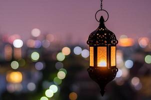 hängande lykta med natt himmel och stad bokeh ljus bakgrund för de muslim fest av de helig månad av ramadan kareem. foto