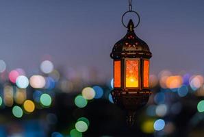 hängande lykta med natt himmel och stad bokeh ljus bakgrund för de muslim fest av de helig månad av ramadan kareem. foto