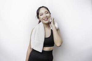 sportigt asiatisk kvinna Framställ med en handduk på henne axel, trött efter träna foto