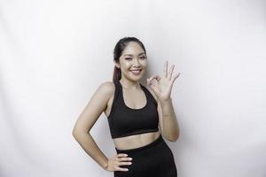 upphetsad sportig asiatisk kvinna bär en sportkläder är ger ett ok hand gest isolerat förbi en vit bakgrund foto