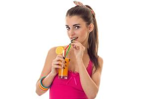 en ung flicka i en ljus t-shirt innehav en glas av juice och dryck den foto