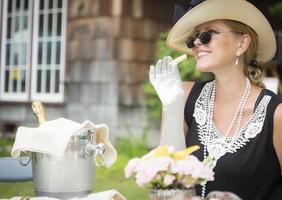 tjugoårsåldern klädd kvinna äter och dricka champagne på utomhus- fest foto