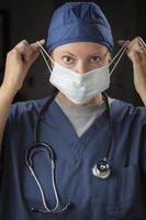kvinna läkare eller sjuksköterska sätta på skyddande ansikte mask foto