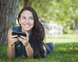blandad lopp ung kvinna textning på cell telefon utanför foto