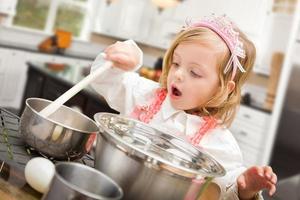 söt bebis flicka spelar laga mat med kastruller och kokkärl i kök foto