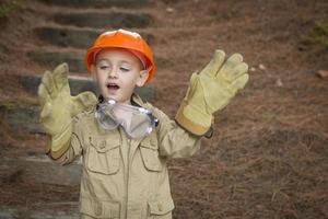 bedårande barnpojke med stora handskar som spelar hantverkare utanför foto