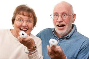 Lycklig senior par spela video spel med fjärrkontroller foto