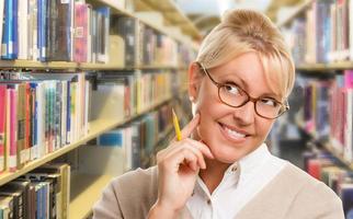 skön uttrycksfull studerande eller lärare med penna i bibliotek. foto