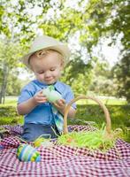 söt liten pojke som njuter av sina påskägg utanför i parken foto