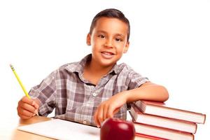 förtjusande latinamerikan pojke med böcker, äpple, penna och papper foto