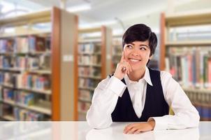 ung kvinna blandad lopp studerande dagdrömma i bibliotek ser till de vänster. foto