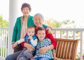 senior vuxen kinesisk par Sammanträde med deras blandad lopp barnbarn foto