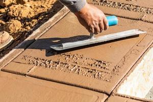 konstruktion arbetstagare använder sig av murslev på våt cement formning hantera runt om ny slå samman foto