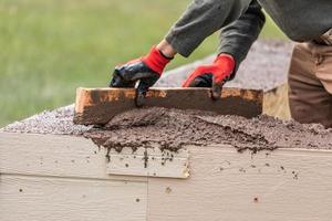 konstruktion arbetstagare utjämning våt cement in i trä inramning foto