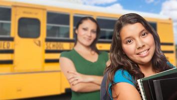 latinamerikan mor och dotter nära skola buss. foto
