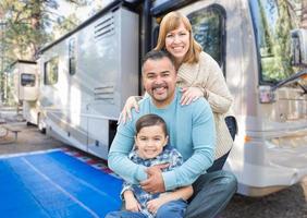 Lycklig ung blandad lopp familj i främre av deras skön rv på de campingplats. foto