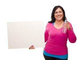 latinamerikan kvinna i träna kläder med vatten och tom tecken foto