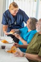 kvinna läkare eller sjuksköterska tjänande senior vuxen par smörgåsar på tabell foto