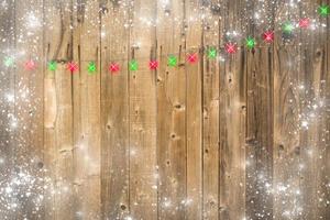 trä- bakgrund med jul lampor och snöig gräns foto