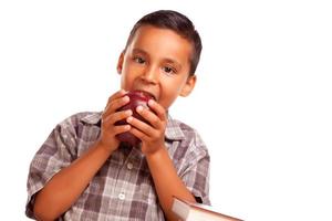 förtjusande latinamerikan pojke äter en stor röd äpple foto