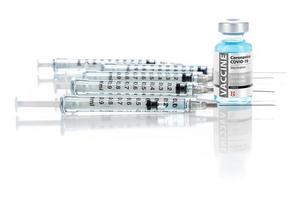 coronavirus covid-19 vaccin injektionsflaska och flera sprutor på reflekterande yta foto