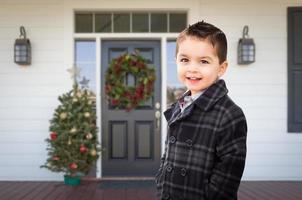 ung blandad lopp pojke på främre veranda av hus med jul dekorationer foto