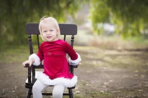 förtjusande liten flicka Sammanträde i henne stol utanför foto