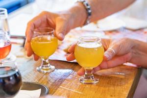 man och kvinna plockning upp små glas av mikro brygga öl på bar foto