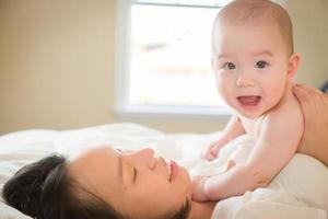 blandad lopp kinesisk och caucasian bebis pojke om i säng med hans mor foto