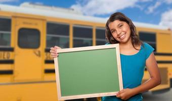 ung kvinna latinamerikan studerande med tom svarta tavlan nära skola buss foto