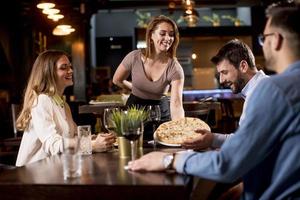 servitör kvinna tjänande grupp av vänner med mat i de restaurang foto