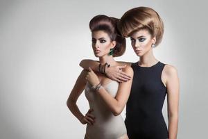 två allvarlig ung flickor med kreativ frisyr ser bort foto