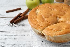 äpple paj Charlotte på vit trä- tabell med färsk äpple och kanel foto