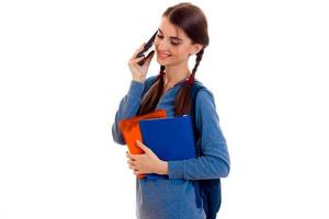 ung skön studerande flicka med ryggsäck Framställ och samtal telefon isolerat på vit bakgrund i studio foto
