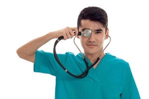 stilig elegant läkare i blå enhetlig med stetoskop Framställ och ser på de kamera isolerat på vit bakgrund foto