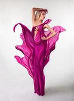 vällustig ung kvinna med kreativ rosa klänning i studio foto