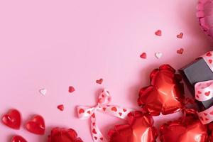 röd hjärta form ballonger, ljus och närvarande låda på rosa bakgrund. valentines dag romantisk bakgrund med kopia Plats foto