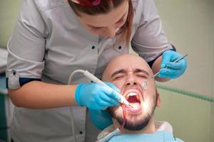 kvinna tandläkare med manlig patient foto