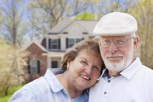 Lycklig senior par i främre av hus foto