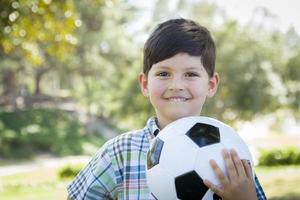 söt ung pojke som leker med fotboll i parken foto