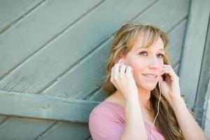 utomhus- porträtt av ung vuxen brun ögon kvinna lyssnande till musik med hörlurar. foto
