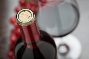 abstrakt vin flaska, kork, glas och röd vindruvor foto