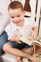 söt ung pojke läsning hans bok foto