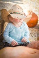 förtjusande bebis flicka med cowboy hatt på de pumpa lappa foto