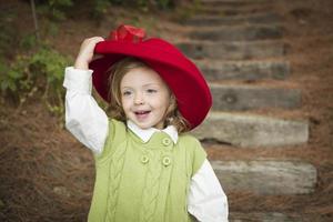 förtjusande barn flicka med röd hatt spelar utanför foto