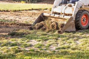 små bulldozer avlägsnande gräs från gård framställning för slå samman installation foto