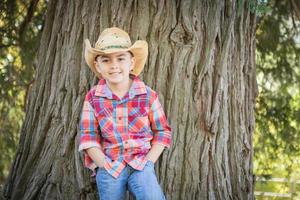 blandad lopp ung pojke bär cowboy hatt stående utomhus. foto