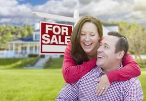 Lycklig par i främre av för försäljning tecken och hus foto