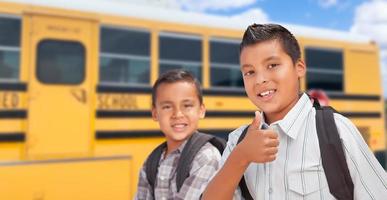 ung latinamerikan Pojkar gående nära skola buss foto
